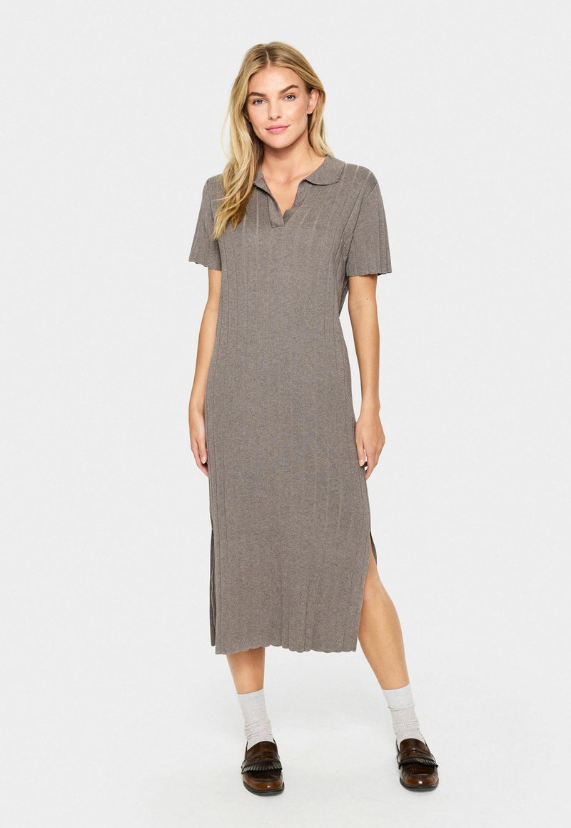 Grå randig midiklänning med korta ärmar, polo-krage, sidofrackar och ett mjukt, texturerat tyg, kombinerad med bruna loafers och ljusa strumpor.
