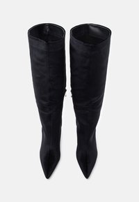 Svart knelang støvlett laget av glatt stoff med spiss tue og vinkelrett design, med glidelås i siden for lukking.