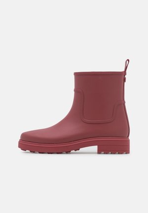 Botte de pluie bordeaux mate à la cheville avec languette de traction, bout arrondi et semelle texturée pour une bonne adhérence, présentée de profil sur fond blanc.