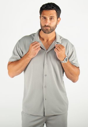 Chemise à manches courtes, col, de couleur gris clair, avec un motif texturé, fermeture à boutons et coupe décontractée.