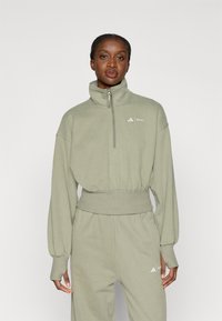 Φωτεινό πράσινο φούτερ με ψηλό γιακά, κλείσιμο με φερμουάρ και ελαστική μέση; διαθέτει διακριτική branding σε λευκό στο στήθος.