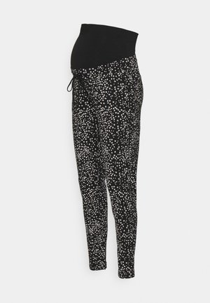 Leggings negros de maternidad con un patrón floral blanco disperso y una cinturilla elástica negra sólida.
