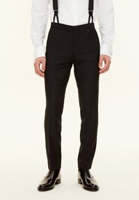 Schwarze Anzughosen im Slim-Fit-Schnitt mit flachem Bund und verstellbaren schwarzen Hosenträgern. Das Material wirkt glatt mit leichtem Schimmer und ist kombiniert mit glänzenden schwarzen Schuhen.