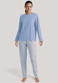 Hellblaues Langarmoberteil kombiniert mit gemusterten Pyjamahosen in Weiß und Blau mit floralem Design, aus weichem Material gefertigt.
