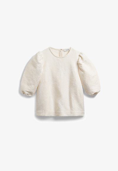 Cream-colored blouse with textured fabric, round neckline, and puffed sleeves. Features a back zipper closure for easy wear.