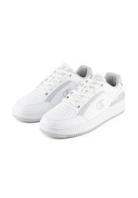 White athletic shoes with a smooth leather upper, grey accents, perforated toe, and laces. Features a textured rubber sole and logo detail.