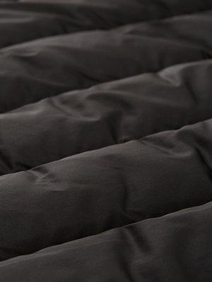 Edredón acolchado negro con una textura suave, que presenta secciones elevadas y un acabado ligeramente brillante, con un detalle de costuras uniformes.