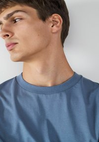 Helle blaue Baumwoll-T-Shirt mit Rundhalsausschnitt. Glatte Textur mit minimalen Falten, Kurzarm und lässiger Schnitt.