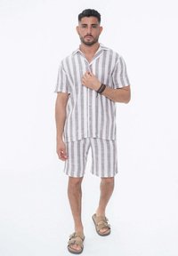 Chemise en lin à manches courtes et shorts assortis, présentant des rayures verticales grises et blanches, avec fermeture à boutons et col.