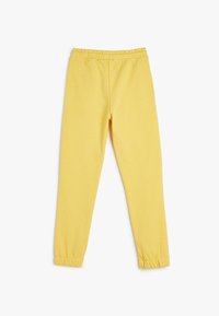 Geel trainingsbroek met een elastische tailleband, taps toelopende pijpen en elastische boorden. Gemaakt van zachte, ademende stof, met een eenvoudige uitvoering.