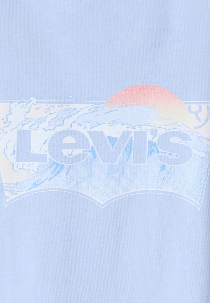 Camiseta de algodón de color azul claro con un gran logo blanco de "Levi's" que presenta un gráfico de una ola y un atardecer en colores pastel.