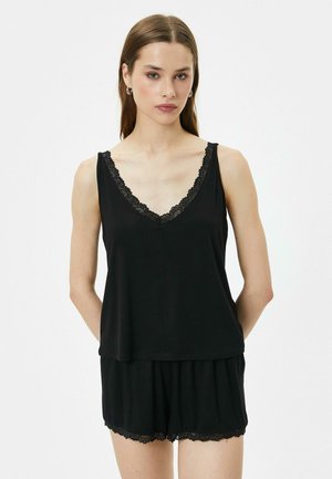 Conjunto de ropa de noche sin mangas en negro que incluye una camiseta de cuello en V con borde de encaje y pantalones cortos a juego con acentos de encaje en el dobladillo. Textura de tela suave.