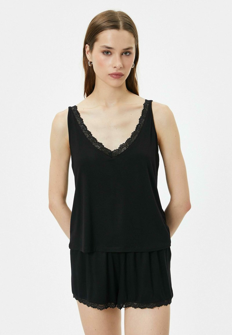 Conjunto de ropa de noche sin mangas en negro que incluye una camiseta de cuello en V con borde de encaje y pantalones cortos a juego con acentos de encaje en el dobladillo. Textura de tela suave.