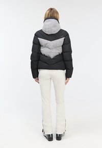Black puffer jacket with a contrasting gray houndstooth-patterned hood and back panel. Features a close fit and sleek design.