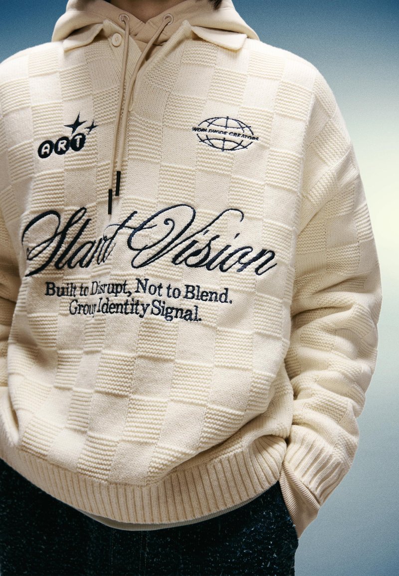 Cremfarbener karierten Pullover mit stickerei, die "Start Vision" und Logos zeigt. Strukturiertem Stoff mit gerippten Bündchen und Saum.