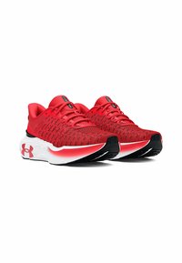 Zapatillas deportivas rojas con parte superior de malla, acentos negros y suela gruesa blanca. Presentan un diseño texturizado y una forma aerodinámica para ofrecer soporte.
