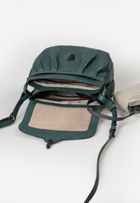 Groene leren rugzak met een geplooid ontwerp, een logo van zwarte hardware en een gevoerde binnenkant met meerdere compartimenten en een suède paneel.