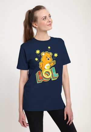 T-shirt bleu marine avec une illustration de dessin animé d'ours levant un doigt, entouré d'étoiles jaunes, et le texte "LOL" en police multicolore et en gras.