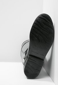 Czarne skórzane botki z teksturowaną gumową podeszwą, kanciastego kształtu i srebrnymi akcentami klamry. Posiadają charakterystyczny wzór bieżnika.