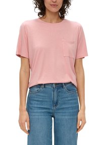 Lichtroze t-shirt met korte mouwen, een ronde hals en een zakdetail. De stof lijkt zacht en is gecombineerd met blauwe high-waisted jeans.