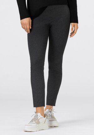 Leggings grigio scuro in materiale elasticizzato, con vestibilità slim e lunghezza alla caviglia, abbinati a sneakers bianche chunky.