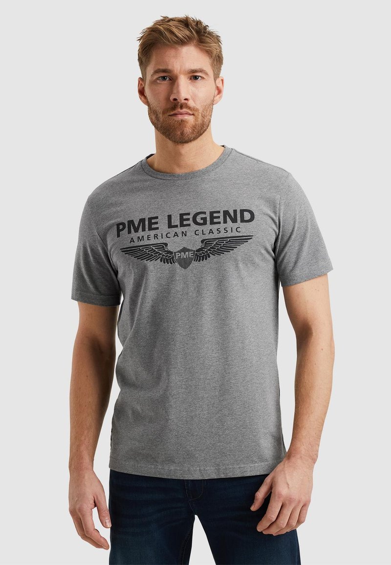 Camiseta de manga corta gris hecha de algodón, con un gran estampado gráfico negro que dice "PME LEGEND AMERICAN CLASSIC" y acentos de alas.