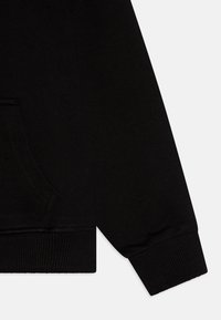 Sudadera negra con una textura suave, que presenta un bolsillo canguro y puños de canalé para un ajuste ceñido. Diseño minimalista sin patrones visibles.