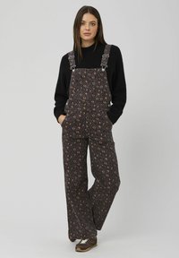 Salopette marron à motifs, ample avec des jambes larges, arborant un imprimé léopard. Bretelles réglables et poches avant.