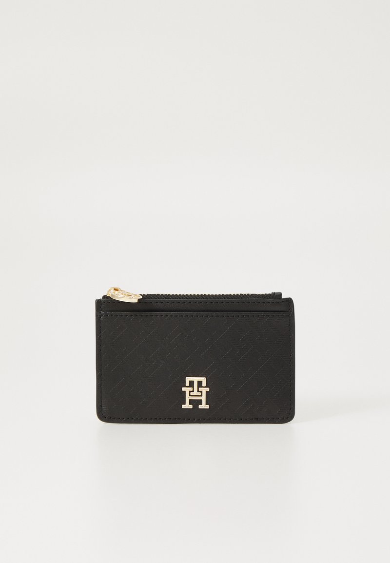 Portefeuille noir texturé avec fermeture zippée, accent logo doré et motif géométrique. Design compact adapté aux cartes et petits objets.