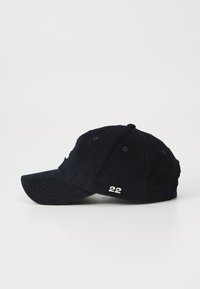 Casquette en velours côtelé marine avec une visière courbée, arborant un logo brodé blanc et "22" sur le côté, avec six trous de ventilation pour la respirabilité.