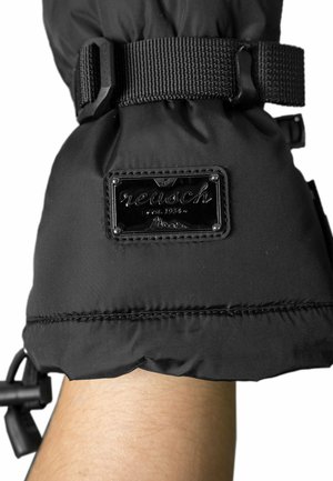 Black insulated glove with a textured fabric, adjustable strap, and a shiny black logo patch featuring "reusch est. 1934." on the wrist area.