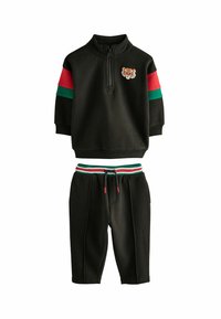 Black cotton tracksuit featuring a zip collar top with a tiger embroidery, red and green stripes on sleeves, and matching drawstring shorts.