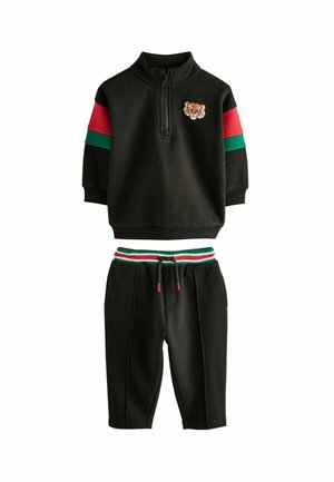 Black cotton tracksuit featuring a zip collar top with a tiger embroidery, red and green stripes on sleeves, and matching drawstring shorts.