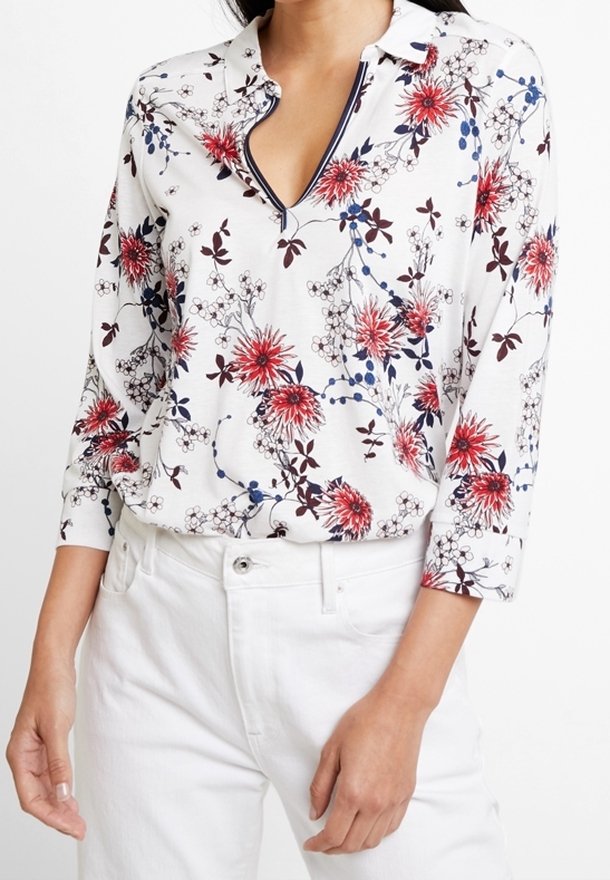 Blumenmuster-Bluse mit langen Ärmeln in Weiß, mit roten und blauen Blumenmustern, einem Kragen und einer halben Knopfleiste, aus weichem Stoff gefertigt.