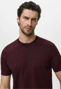 Pull à manches courtes bordeaux en maille lisse avec un col rond, doté de poignets côtelés et d'une coupe ajustée. Design uni.