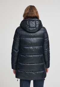 Svart puffjacka med huva, med quiltade detaljer, en slät textur och justerbara dragsnören i nederkant.