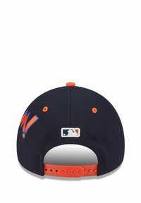 Marineblaues Baseballcap mit oranger Snapback, ausgestattet mit erhabenem "M!" Schriftzug und einem weißen MLB-Logo auf der Rückseite. Glatte Stoffstruktur.