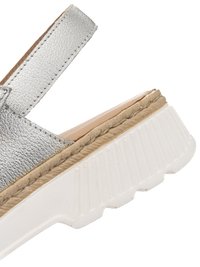 Silver leather sandal strap attached to a thick white ridged sole with beige stitching along the edge.
