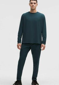 Dunkeltürkises Langarmoberteil und passende Hose aus leichtem, dehnbarem Stoff. Einfaches Design ohne sichtbare Muster oder Akzente.