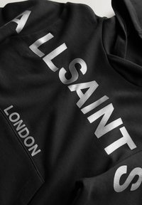 Sudadera negra con capucha que presenta un gran texto en mayúsculas plateado "ALLSAINTS" en la parte frontal y "LONDON" por debajo, fabricada con una tela suave y un ajuste clásico.