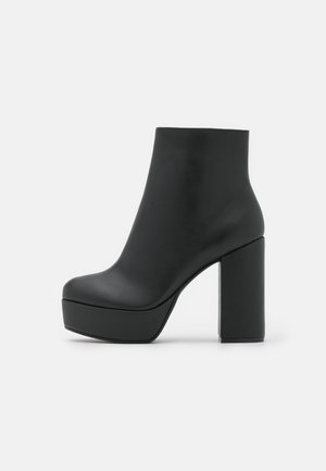 Czarne skórzane botki za kostkę o gładkiej fakturze, z masywną platformą i kwadratowym wysokim obcasem. Elegancki i minimalistyczny design.