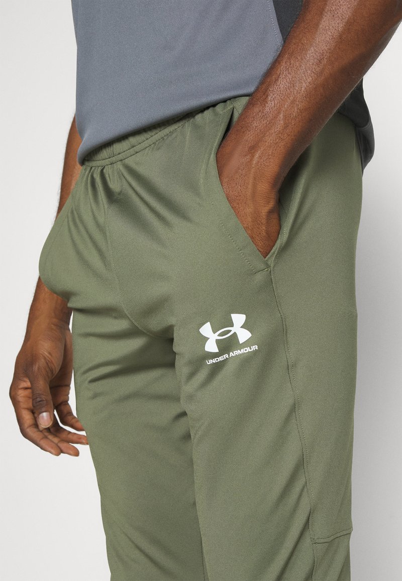 Pantalons de sport vert olive avec une taille élastique, des poches latérales et un logo Under Armour blanc. Fabriqués en tissu durable et lisse.