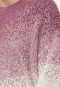 Sweter dziergany z gradientem od głębokiego różu do bieli. Miękka, puszysta faktura z delikatnymi cętkami i okrągłym dekoltem.