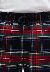 Καρό πυτζάμα με συνδυασμό από κόκκινες, πράσινες, μαύρες και μπλε αποχρώσεις, με κορδόνι στη μέση και απαλό, υφασμάτινο υλικό.