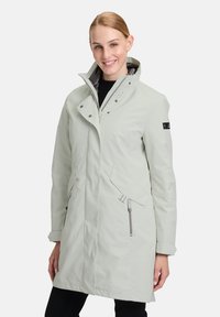 Manteau imperméable gris clair avec un col haut, fermeture éclair et bouton-pression, deux poches latérales et détails noirs. Texture extérieure lisse.