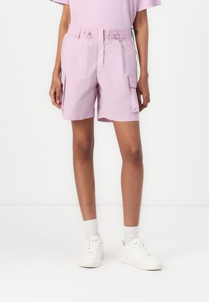 Shorts lilas avec une taille élastique, deux poches cargo latérales et une texture légère. Assortis avec des baskets et des chaussettes blanches.