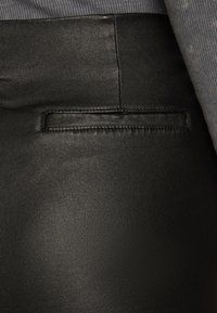 Höga svarta byxor i konstläder med en slät yta, med en liten bakficka och subtila sömdetaljer.