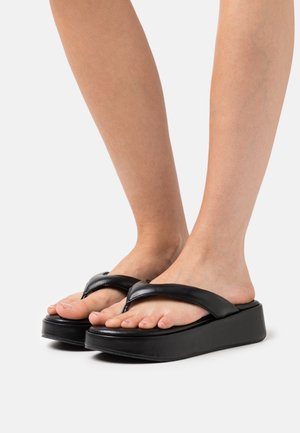 Zwarte teenslippers met een platte, textuurzool en een dikke plateauzool. De bandjes zijn gemaakt van glad materiaal en hebben een V-vormig ontwerp.