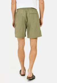 Groene cargoshorts met een elastische tailleband, een achterzak en een zijzak, gemaakt van lichtgewicht materiaal.