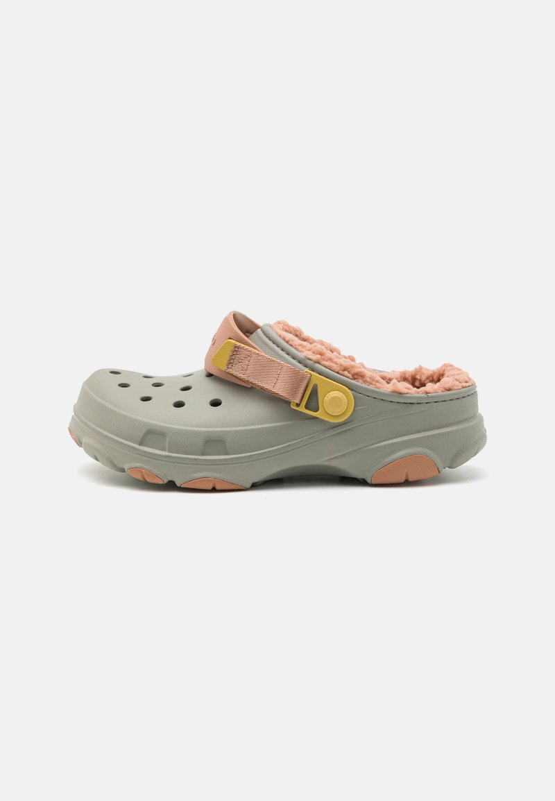 Sabot gris clair à enfiler avec doublure pelucheuse pêche, trous de ventilation et bride de talon réglable pêche et jaune sur fond blanc.